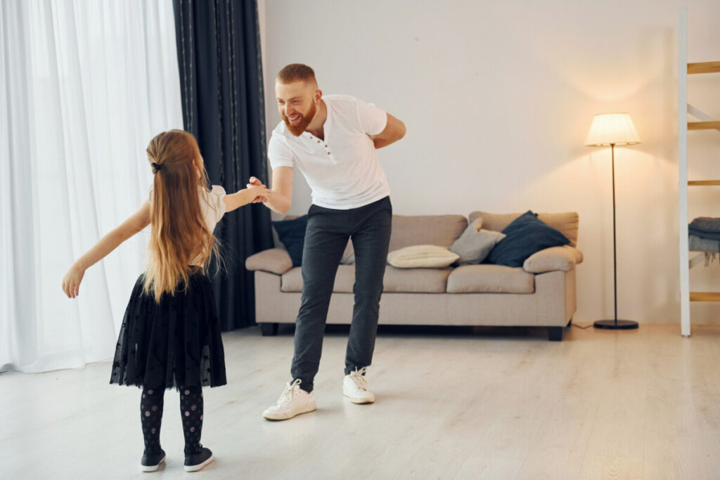 Learning to dance. Father with his little daughter is at home together.