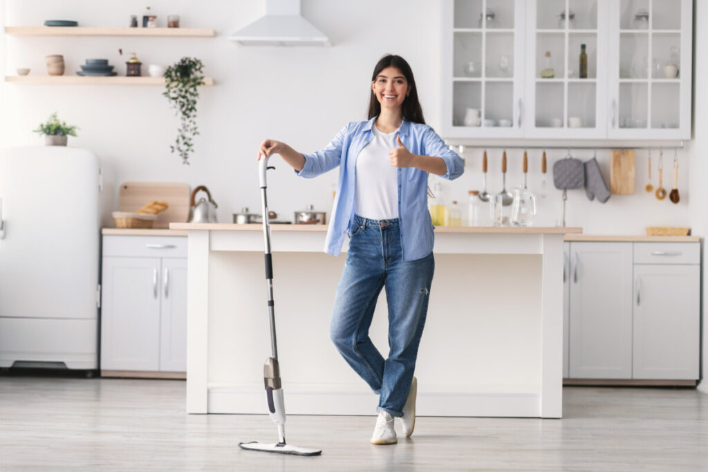Happy woman cleaning floor with spray mop